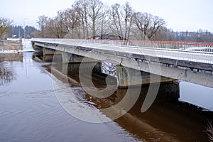 River Aiviekste in Vidzeme, Latvia in winter time. High water level in the river, dark January day. Bridge over the