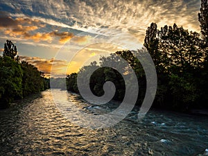 River Arve, Switzerland, in deep shadow as the sky is illuminated by the rising sun.