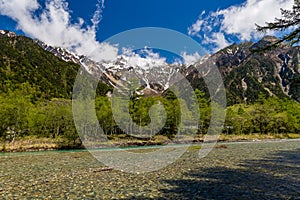 River Azusa flowing through the highland Kamikochi valley with towering, snow-capped mountains behind