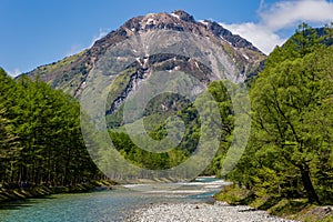 River Azusa flowing through the highland Kamikochi valley with towering, snow-capped mountains behind