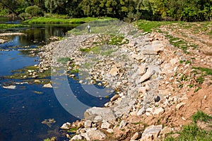 River bank fortified from erosion by stones and concrete debris