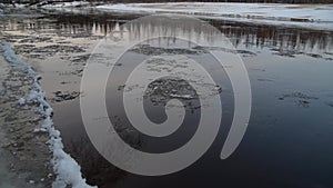 River bank with moving ice on the water at sunset, ice melting, ice drift, winter scenery