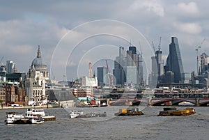 River barges on the thames in late afternoon with the city of london modern financial buildings and historic center visible in the