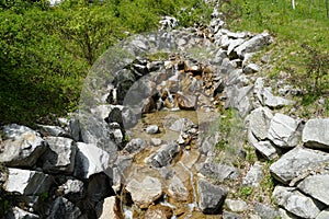 River basin bordered with large stones in Alpine Engelberg Region Obwalden canton in Switzerland on early spring with low water le