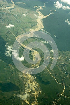 River bed with sandy banks in a green valley of fields and forests from a great height. aerial photography white clouds above the