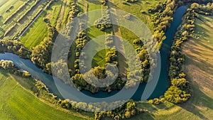 River bend surrounded by fields from bird`s eye view.