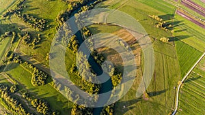 River bend surrounded by fields from bird`s eye view.