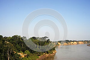 River tied up to pier along muddy and grassy river bank with view to other shore in Puerto Maldonado in Peru and the Amazon