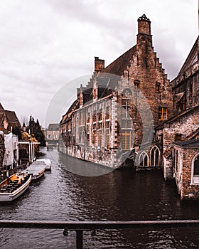 a river and buildings in brugey, belgium with a boat at the water