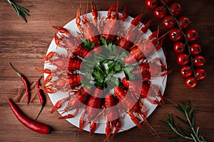 River cooked crayfish on a white plate with cherry tomatoes and chili peppers