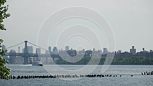 River cruise ship catamaran powers past the Brooklyn Bridge on New York\'s east river