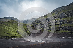 River delta with black sand beach, rocks and high cliffs in Faroe islands, close to village Saksun in Faroese island