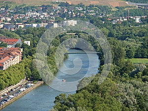 River with dense green shoreline trees flowing through the city with dense buildings, Bavaria