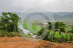 River and dirt road with mountains and lush vegetation at Ring Road in Cameroon, Africa