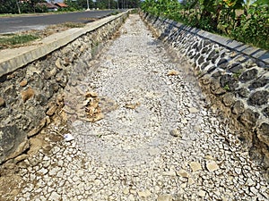 The river dries up on the side of the road, with cracked soil