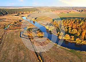 River at field in the fall season. Golden autumn landscape. Aerial view of the wild river on sunset in autumn season.