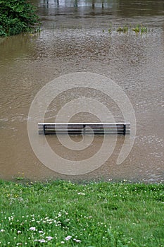 River flood with flooded park bench