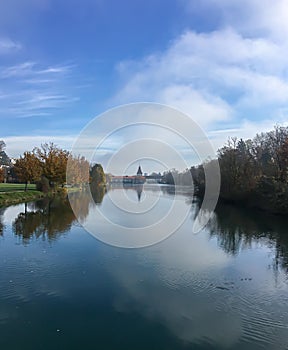 landscape in autumn with river flow with reflections toward building with tower