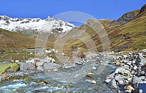 River flowing in a meadow with mountain with snow