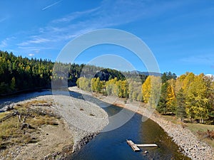 River flowing past woods with autumn colors