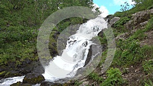 The river flows down the mountainside, forming a waterfall.