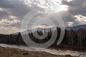 The river flows at the foot of the mountain ridge