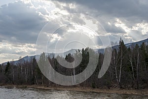 The river flows at the foot of the mountain ridge