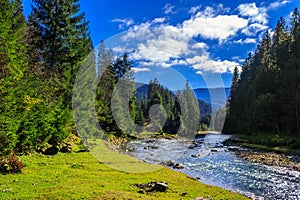 River flows by rocky shore near the autumn mountain forest