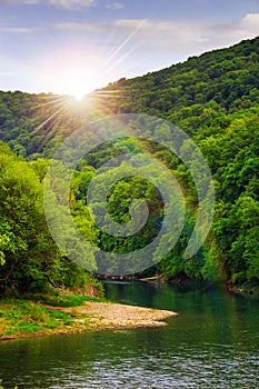 River flows by rocky shore near the autumn mountain forest