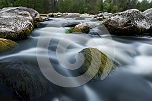 River flows among the stones. Blurry water.