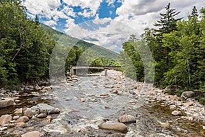 River through forest near the White Mountains, a bridge in background