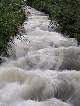River Garw in full flood tumbling down the hillside framed by overhanging trees, Blaengarw, Mid Glamorgan, South Wales