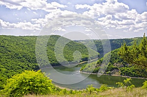 River between green hills with the blue sky