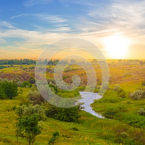 river among green prairie at the sunset