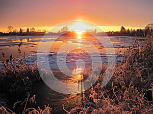 River Atmata , homes and snowy trees in sunset colors, Lithuania