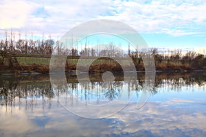 River in the italian countryside in winter with the sky casted in the water