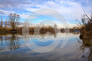 River in the italian countryside in winter with the sky casted in the water