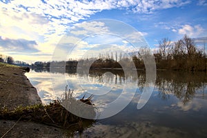 River in the italian countryside in winter with the sky casted in the water