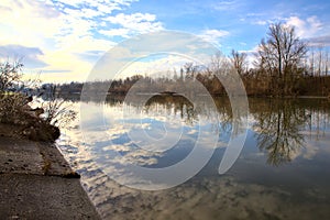 River in the italian countryside in winter with the sky casted in the water