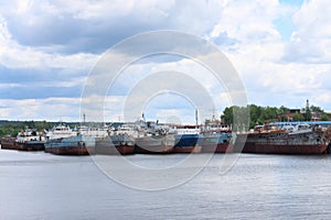 River with many rusty cargo ships and sky with clouds