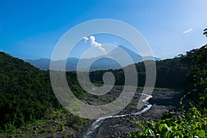 River in the middle of the jungle with two volcanoes in the background photo