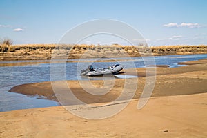 River motor boat near sandy river bank with golden dunes and blue water