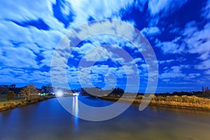 A river at night, with moonlit clouds in the sky above