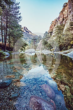 River with pebbles, mountains and picturesque forest. Enchanting and evocative landscape.