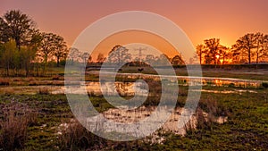 River and ponds in a Dutch landscape during sunset near Almelo