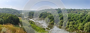 River with rapids and stones outcrops, banks overgrown with trees