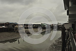 river reflection muddy water moored boat stilt houses cloudy sky