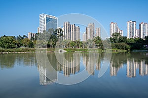 The river reflects the modern city buildings under the blue sky