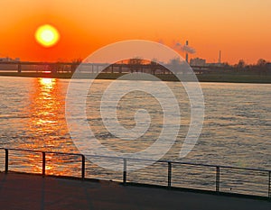 River Rhine near DÃ¼sseldorf, sunset with view to the Oberkasseler bridge, in the foreground railings