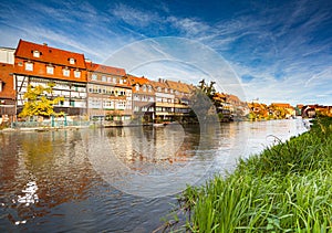 a river running through a city next to tall buildings and tall grass on both sides of the river bank